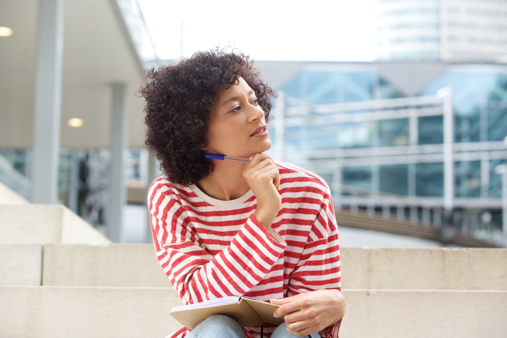 Christian woman with pen and journal wondering what is God's purpose for me
